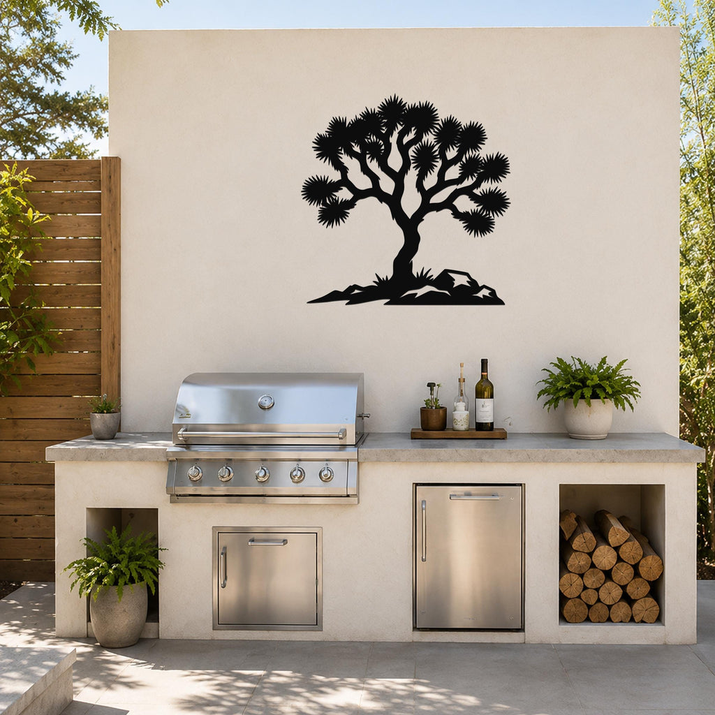 Black metal wall art silhouette of a Joshua tree with spiky branches and rocky base, mounted on an outdoor wall above a kitchen counter.