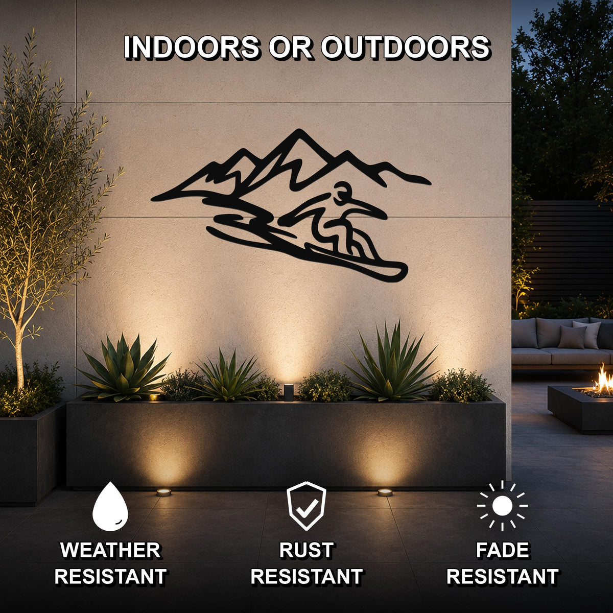 Black metal wall art featuring a snowboarder silhouette in front of mountain peaks, mounted on an outdoor wall above a planter in a modern patio setting.
