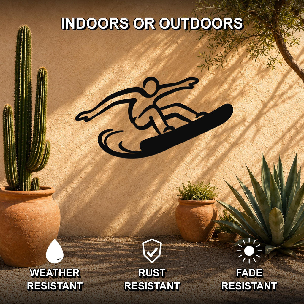 Black metal snowboarder wall art silhouette with motion lines, mounted on an outdoor stucco wall between potted cacti and succulents.
