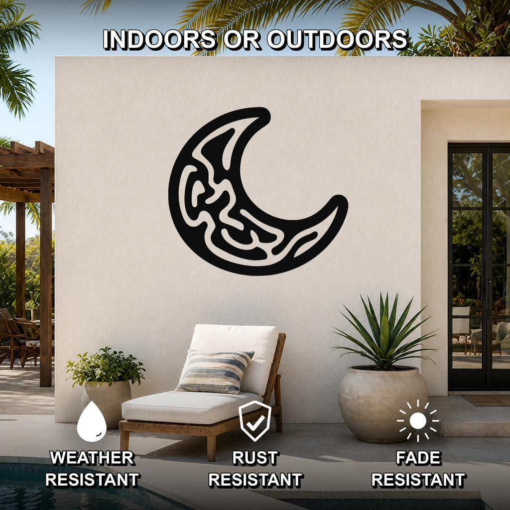 Black metal crescent moon wall art with intricate internal cutouts, mounted on an outdoor patio wall above a lounge chair.