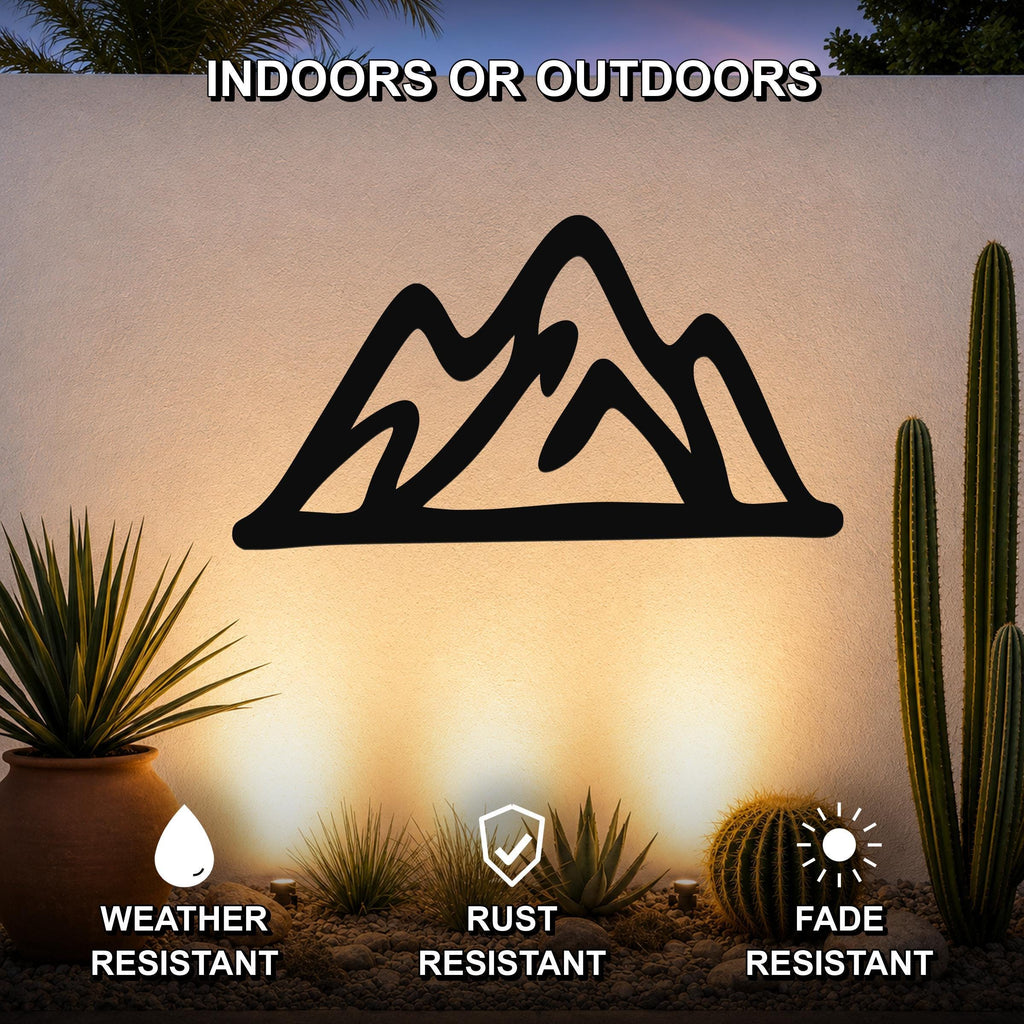 Black metal mountain silhouette wall art with layered peaks, mounted on an outdoor wall above a desert garden with cacti and succulents.