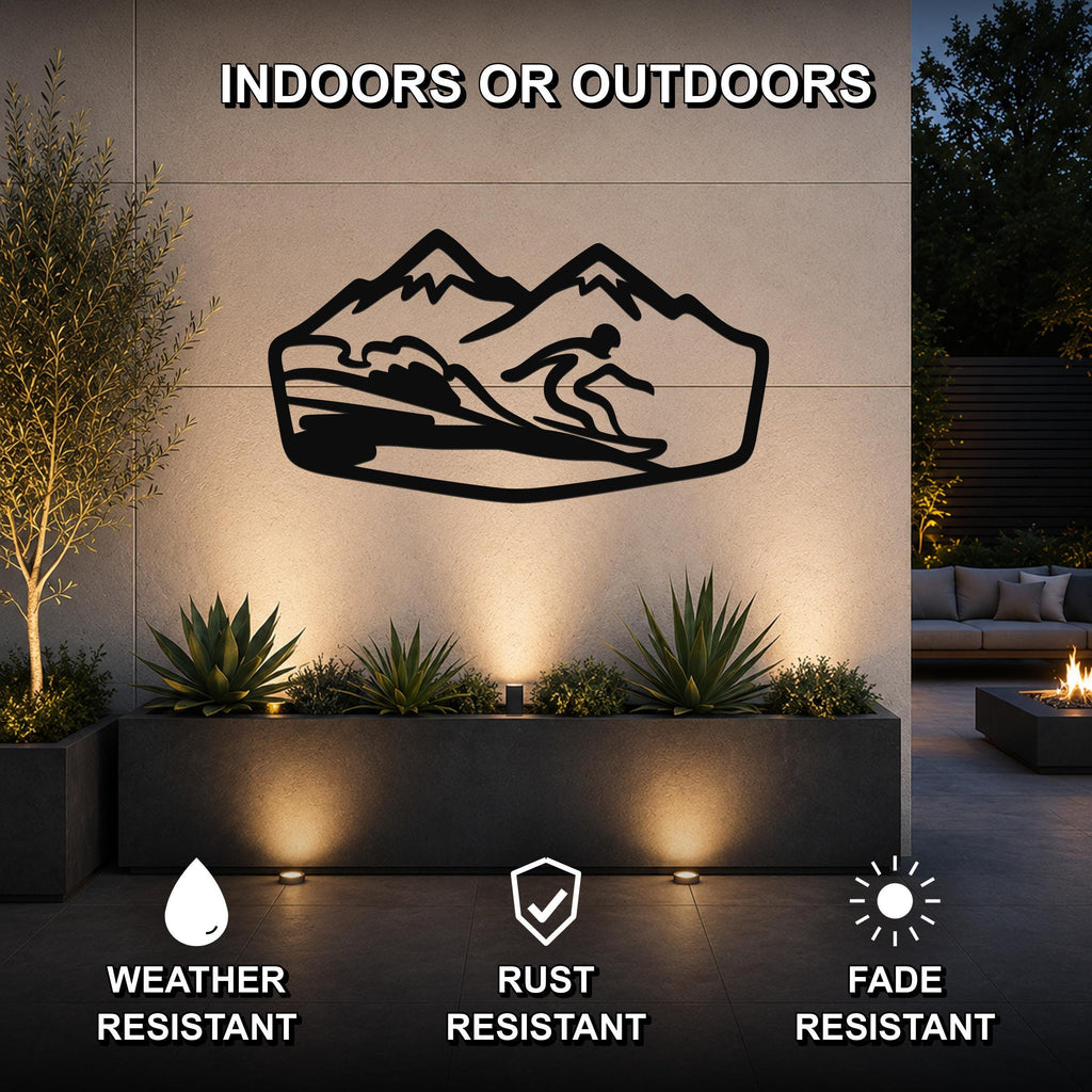 Black metal wall art featuring a snowboarder silhouette in motion against a mountain backdrop, mounted on an outdoor wall above a planter in a patio setting.
