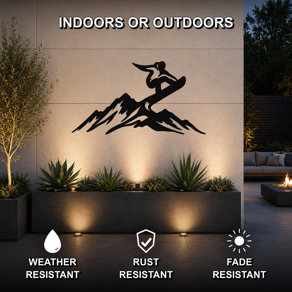 Black metal wall art featuring a snowboarder silhouette above mountain peaks, mounted on an outdoor wall above a planter in a modern patio setting.