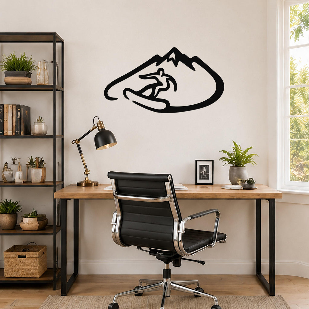 Black metal wall art featuring a snowboarder silhouette inside a mountain outline, mounted above a wooden desk in a home office.