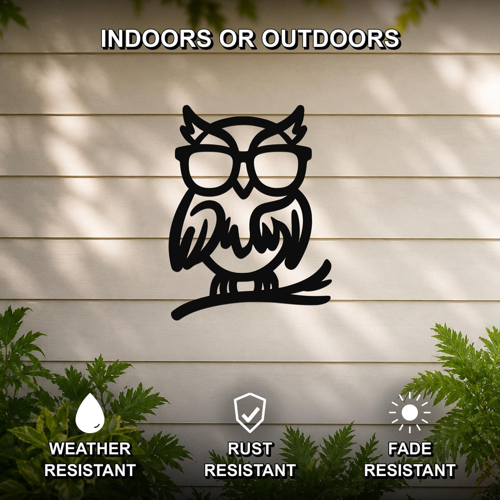 Black metal owl wall art with glasses and a branch silhouette, mounted on a light-colored outdoor wall with greenery, weather resistant, rust resistant, and fade resistant.