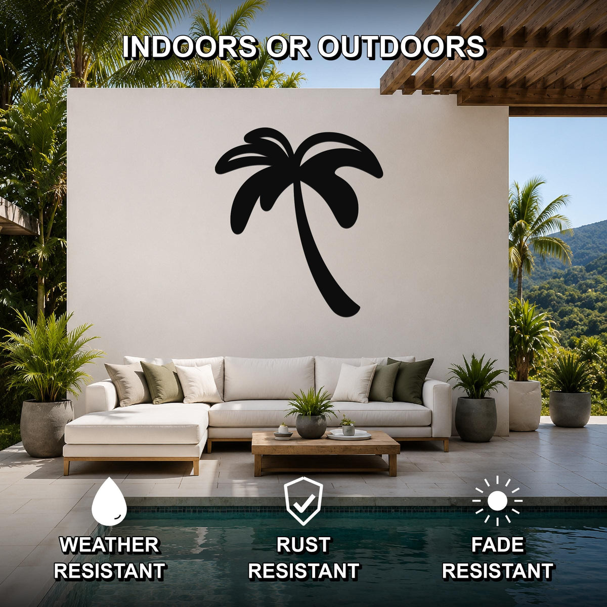 Black metal palm tree wall art silhouette mounted on a white outdoor wall above a white sectional sofa in a patio setting.