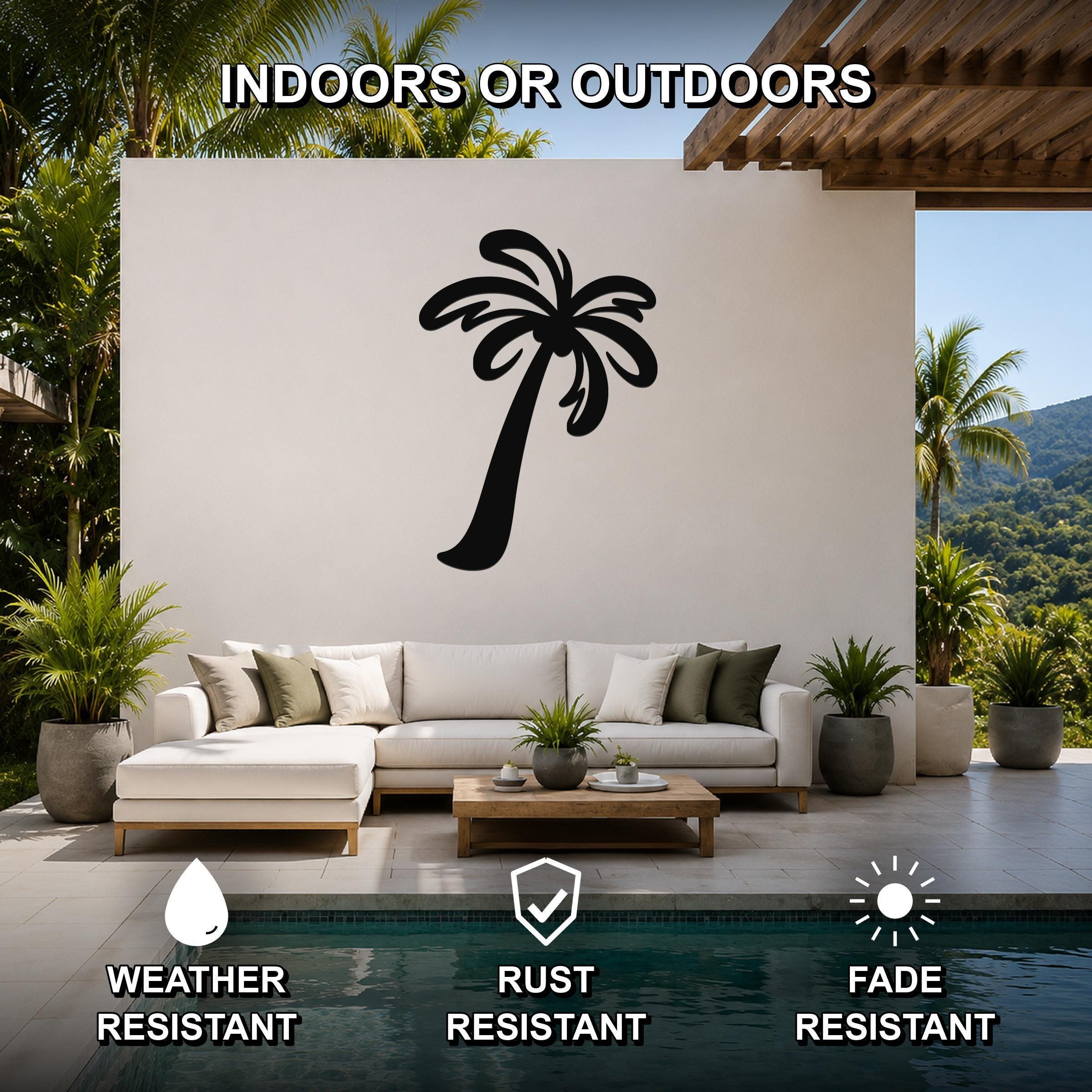 Black metal palm tree wall art silhouette mounted on a white outdoor wall above a white sectional sofa in a patio setting.