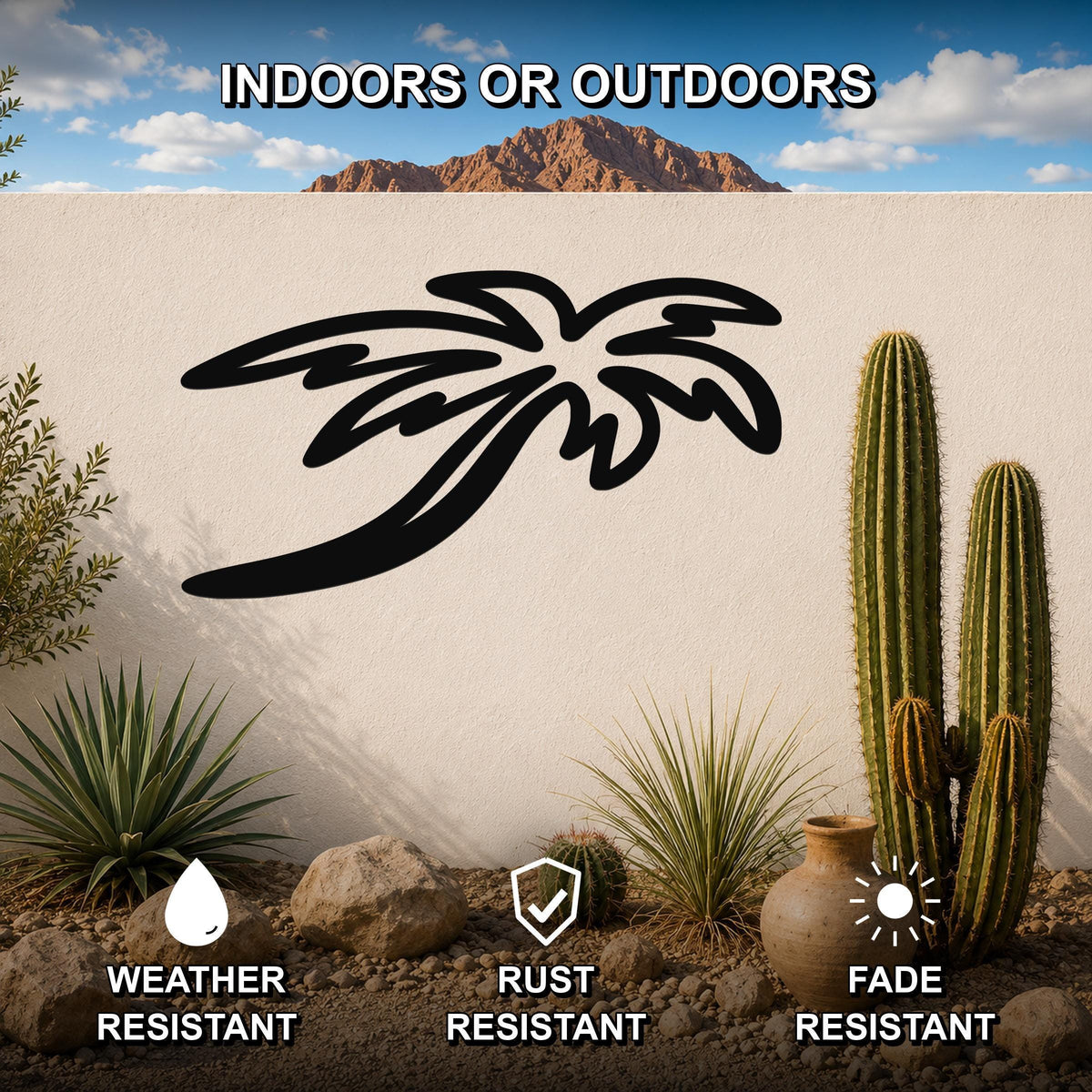Black metal palm tree wall art with flowing frond cutouts, mounted on an outdoor wall in a desert garden setting with cacti and rocks.