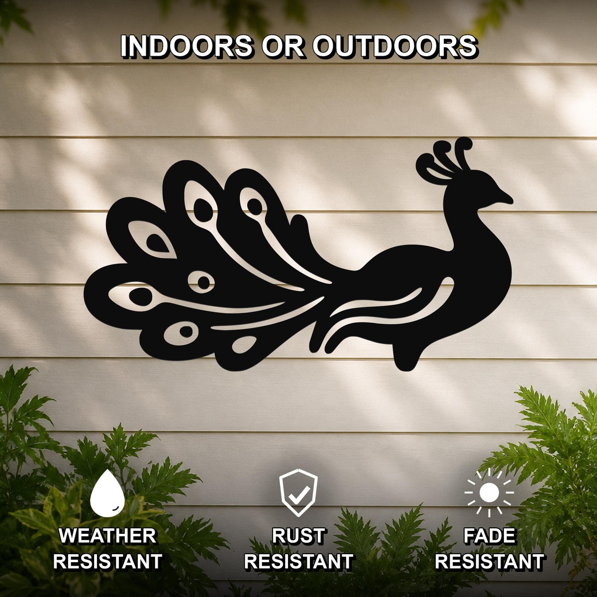 Black metal peacock wall art with detailed feather cutouts, mounted on a light-colored outdoor wall with greenery below.