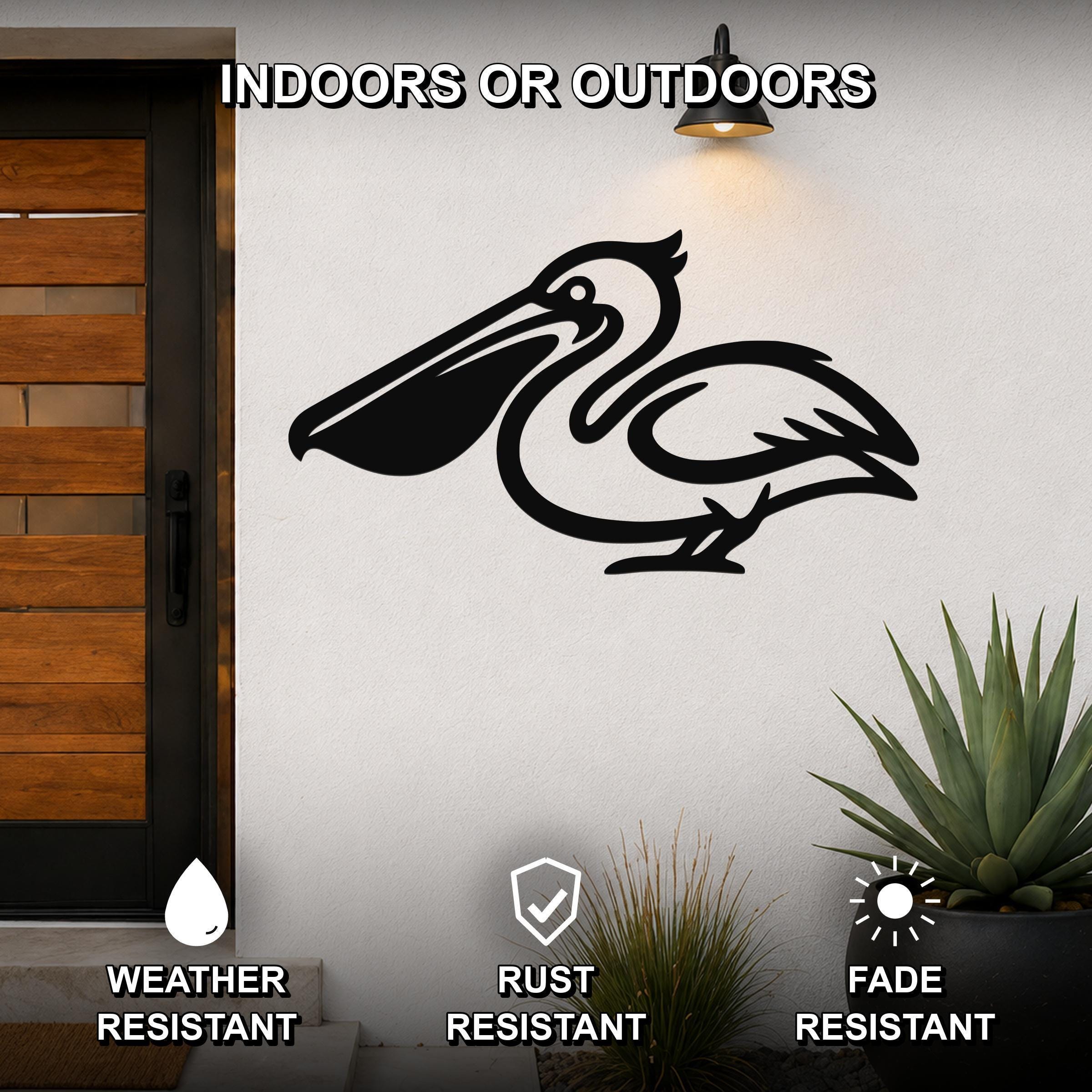 Black metal pelican wall art with a cutout silhouette design, mounted on an outdoor wall beside a wooden door and potted plants.
