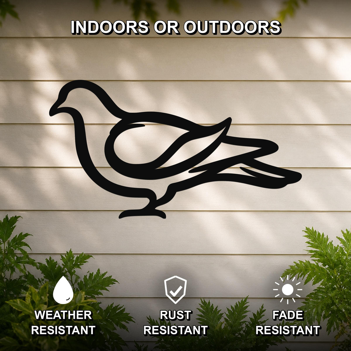 Black metal pigeon wall art silhouette with cutout design, mounted on a light-colored outdoor wall with greenery below.
