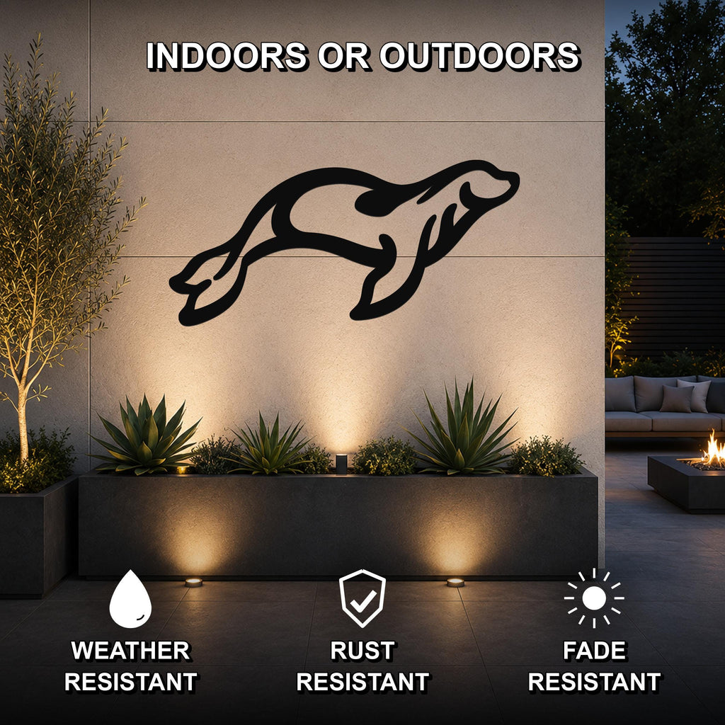 Black metal sea lion wall art with motion-line cutouts, mounted on an outdoor wall above a planter in a modern patio setting.