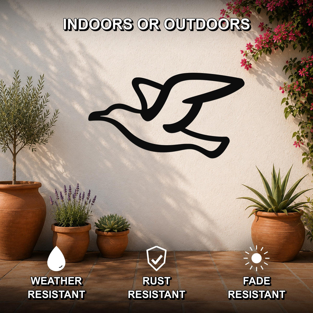 Black metal seagull wall art silhouette mounted on an outdoor patio wall, surrounded by potted plants and flowers, with text indicating it is weather, rust, and fade resistant.