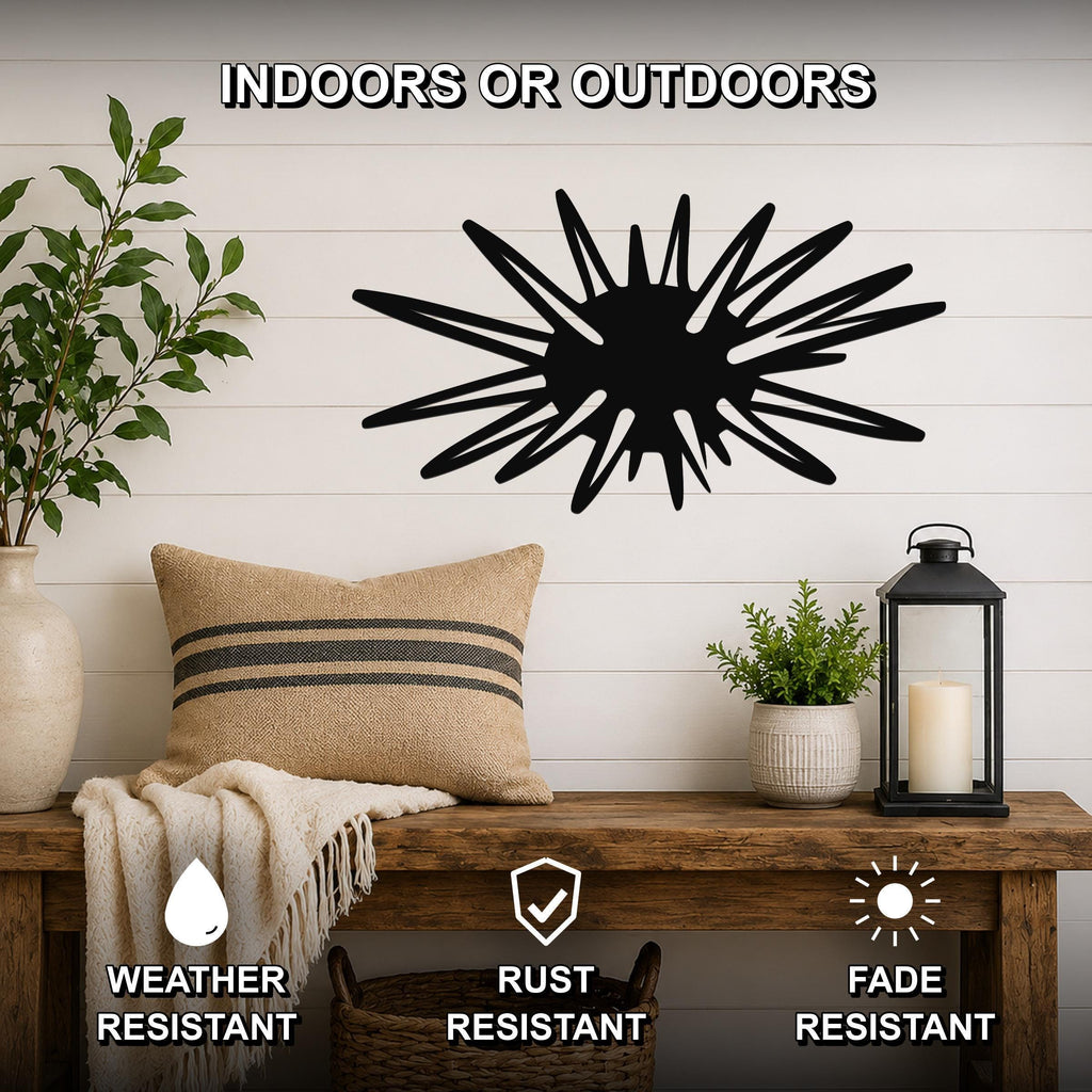 Black metal sea urchin wall art with spiky radial cutouts, mounted on a white shiplap wall above a wooden bench in a living room.