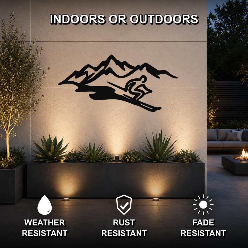 Black metal wall art featuring a skier silhouette and mountain range, mounted on an outdoor wall above a planter in a modern patio setting.