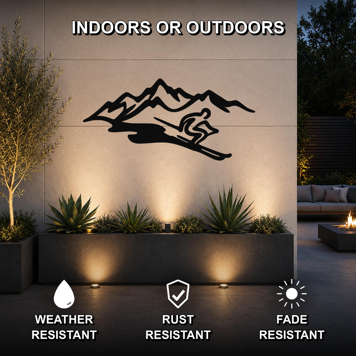 Black metal wall art featuring a skier silhouette and mountain range, mounted on an outdoor wall above a planter in a modern patio setting.