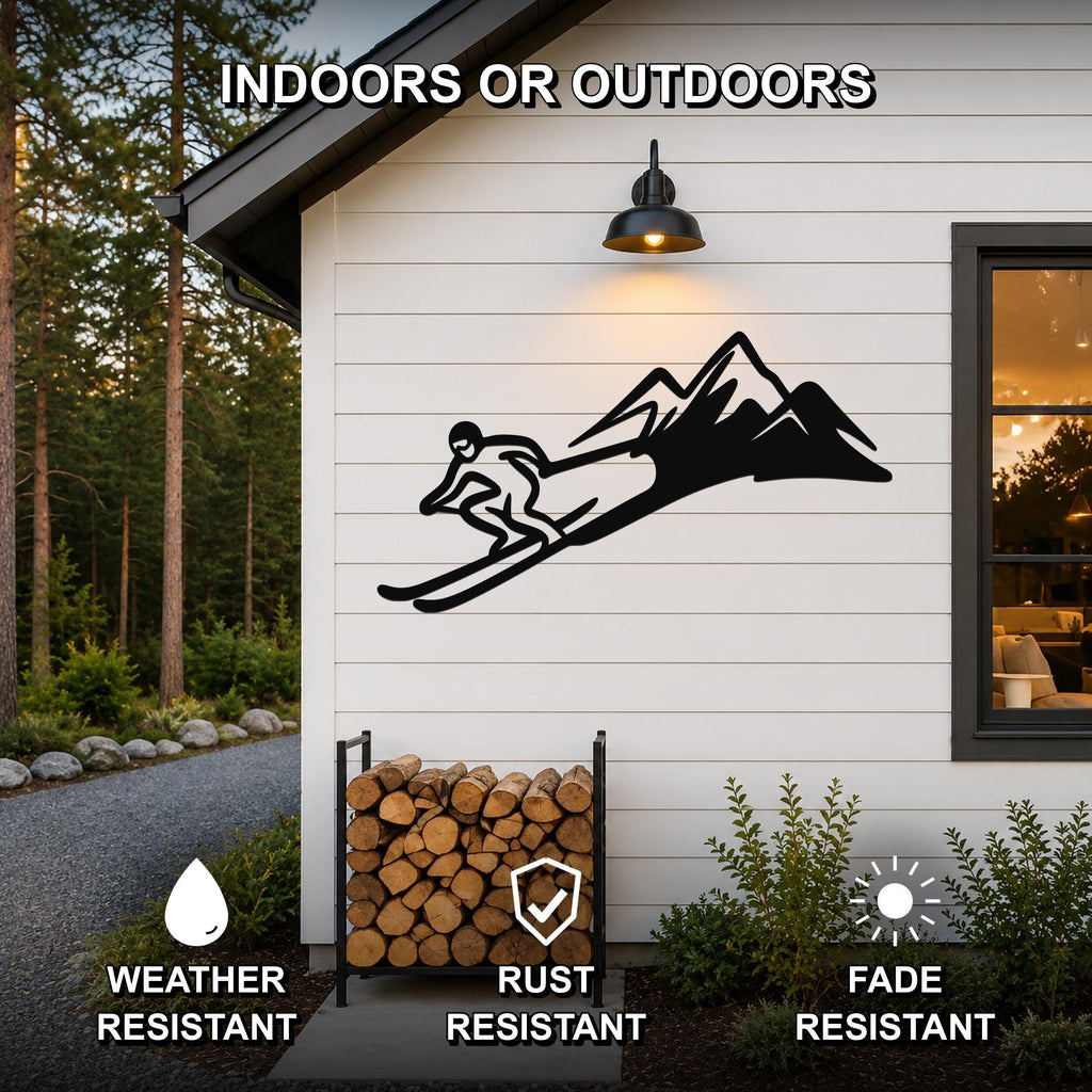 Black metal skier and mountain wall art silhouette mounted on a white exterior wall above a firewood rack, with text indicating it is weather, rust, and fade resistant for indoor or outdoor use.