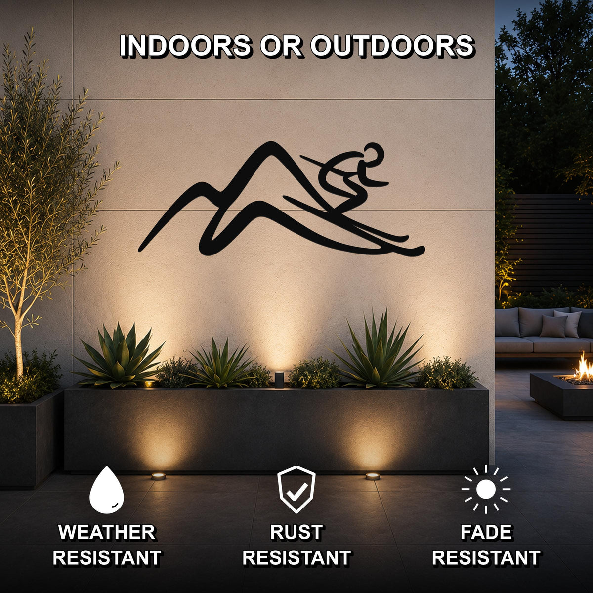 Black metal skier and mountain silhouette wall art mounted on an outdoor patio wall above a planter, with integrated lighting highlighting the design.