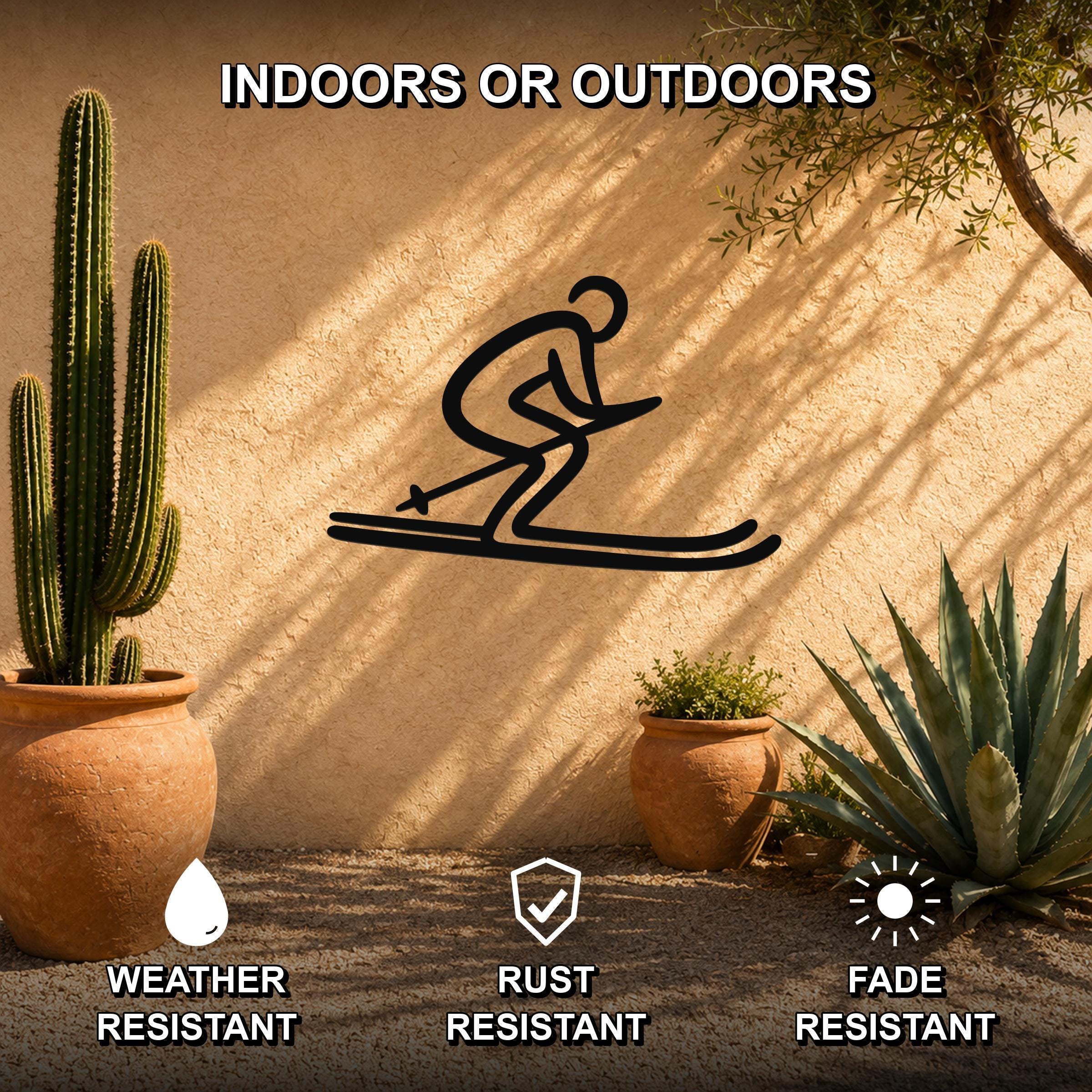 Black metal skiing silhouette wall art with a dynamic skier cutout, mounted on an outdoor stucco wall among potted cacti and succulents.