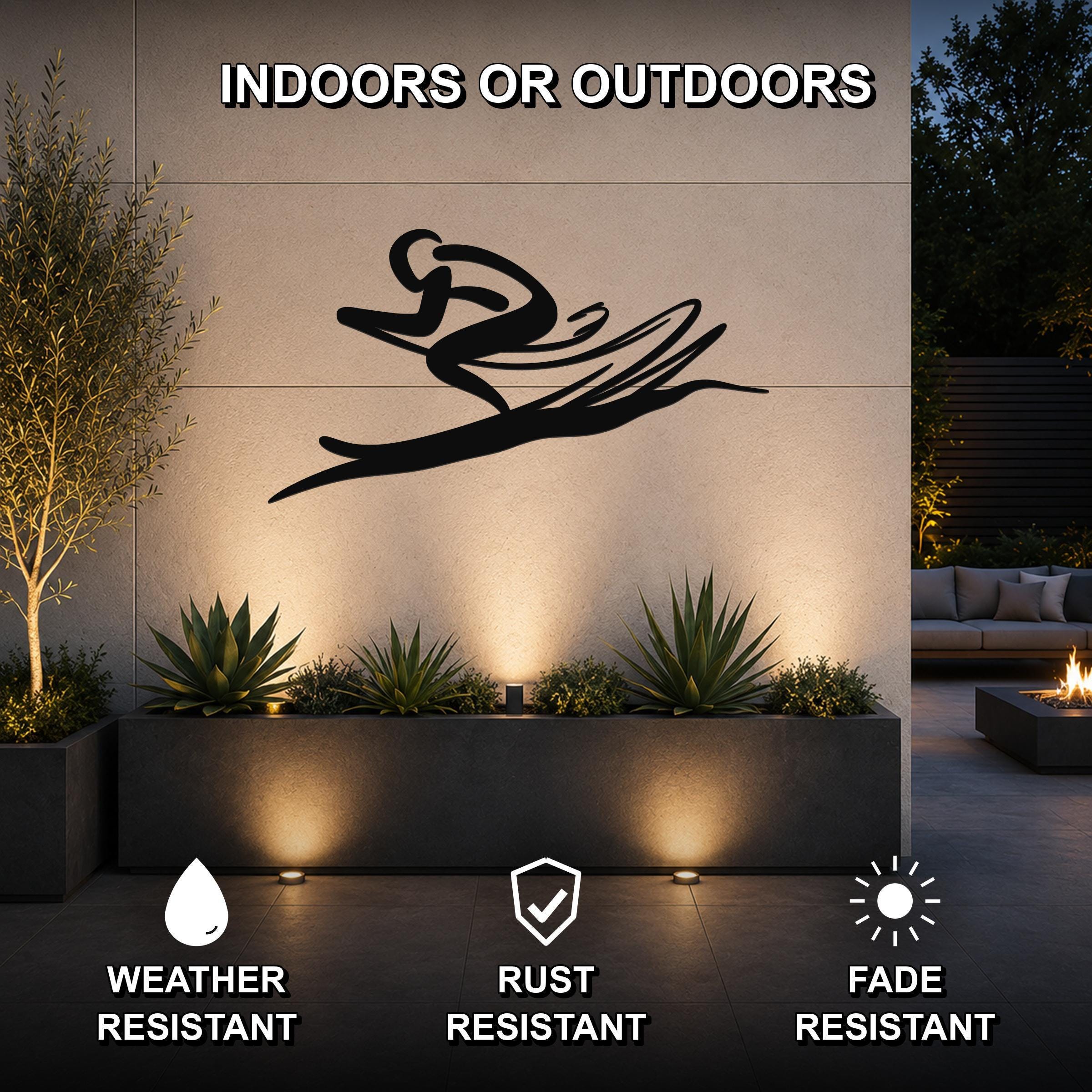 Black metal skiing wall art with motion-line cutouts, mounted on an outdoor wall above a planter in a modern patio setting.