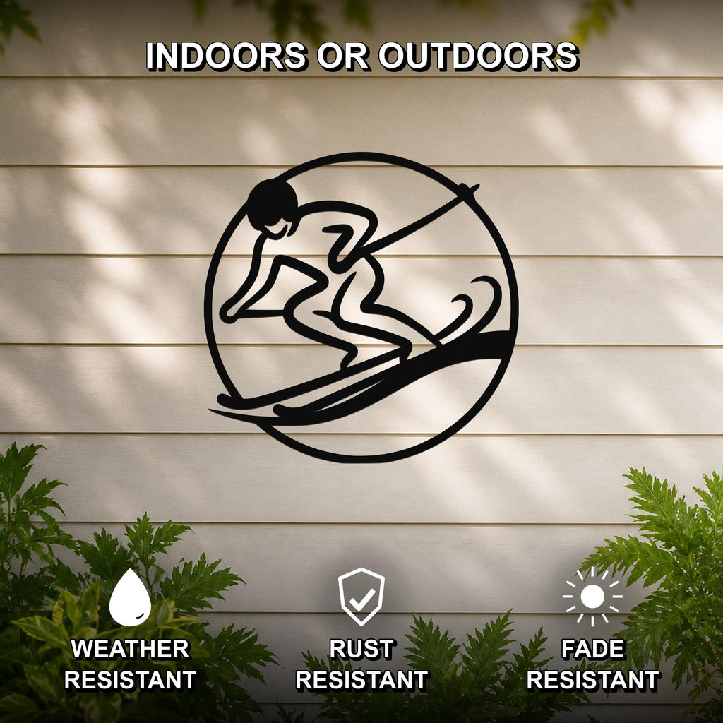 Black metal wall art featuring a circular silhouette of a skier in motion, mounted on a light-colored outdoor wall with greenery below.