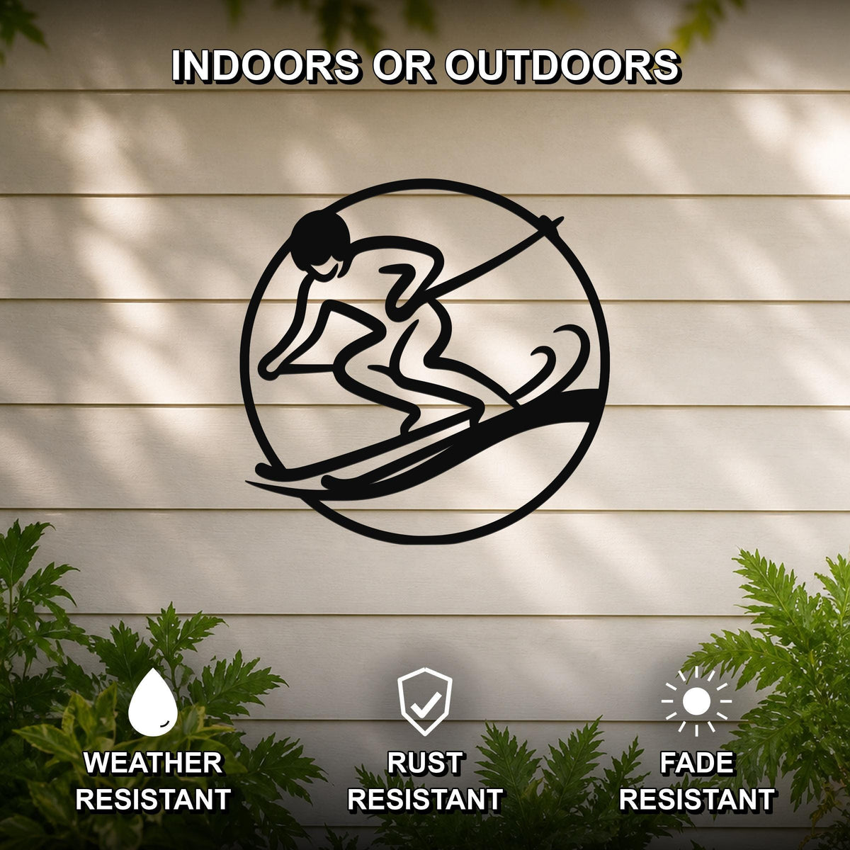 Black metal wall art featuring a circular silhouette of a skier in motion, mounted on a light-colored outdoor wall with greenery below.