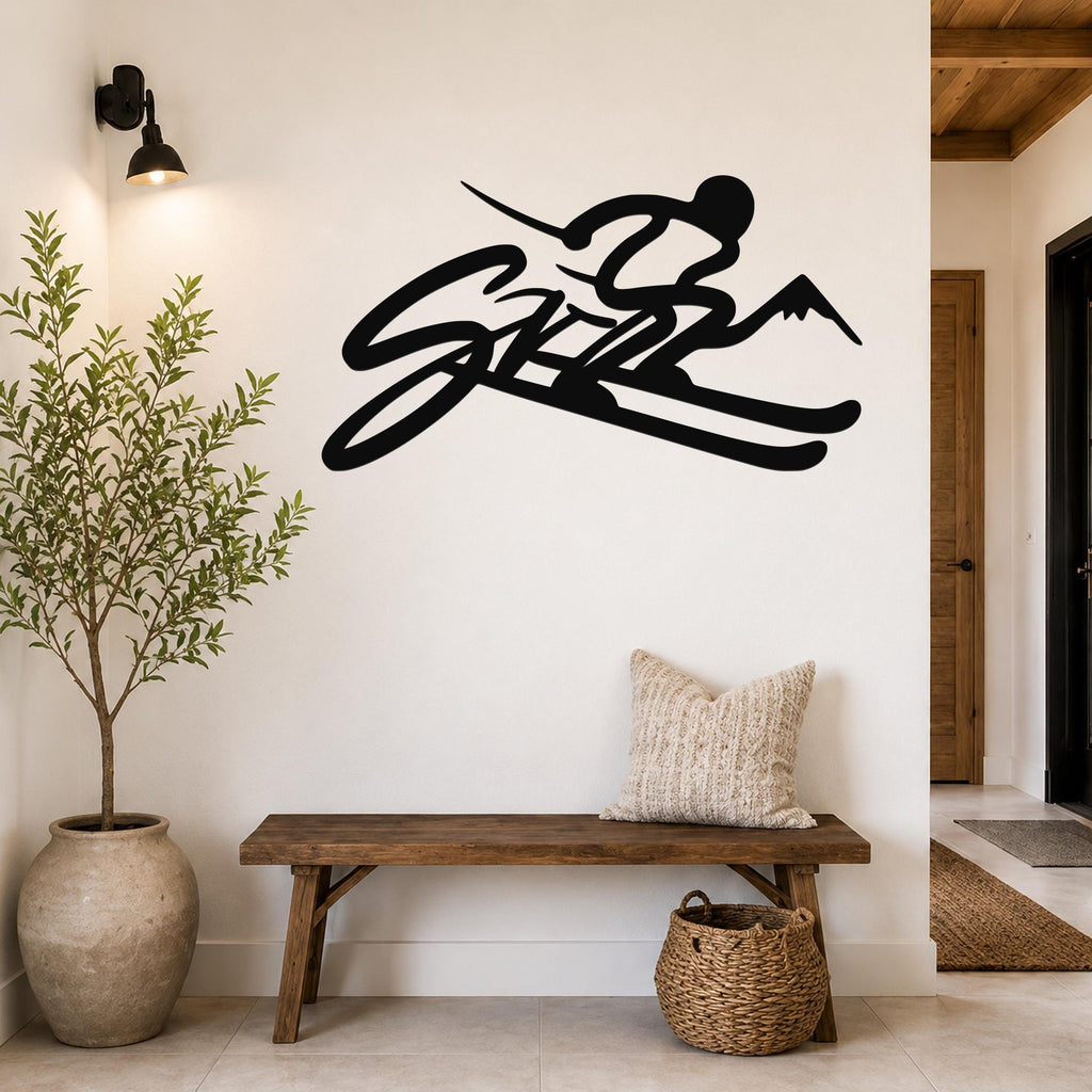 Black metal wall art in a ski silhouette design with mountain peaks, mounted on a white wall above a wooden bench in a modern entryway.