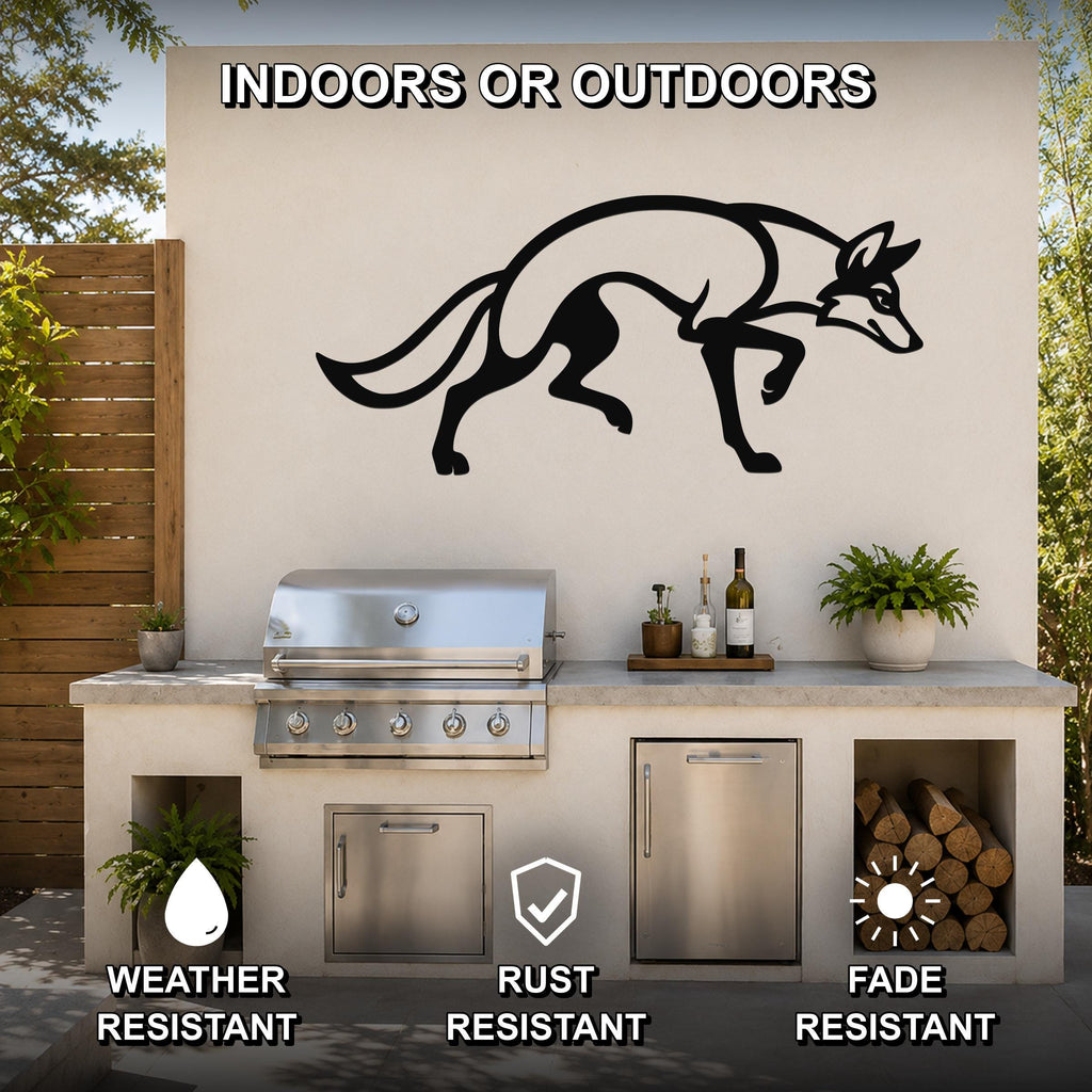 Black metal coyote wall art silhouette mounted on an outdoor kitchen wall above a stainless steel grill, with visible weather, rust, and fade resistance icons.