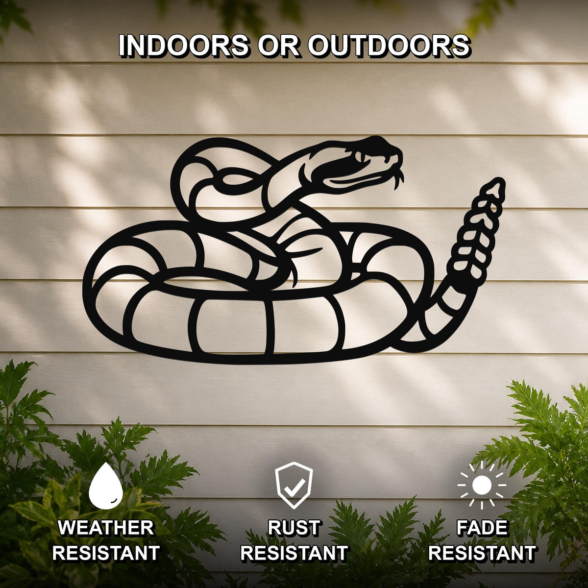 Black metal snake wall art with coiled silhouette and rattlesnake tail, mounted on a light-colored outdoor wall with greenery below.