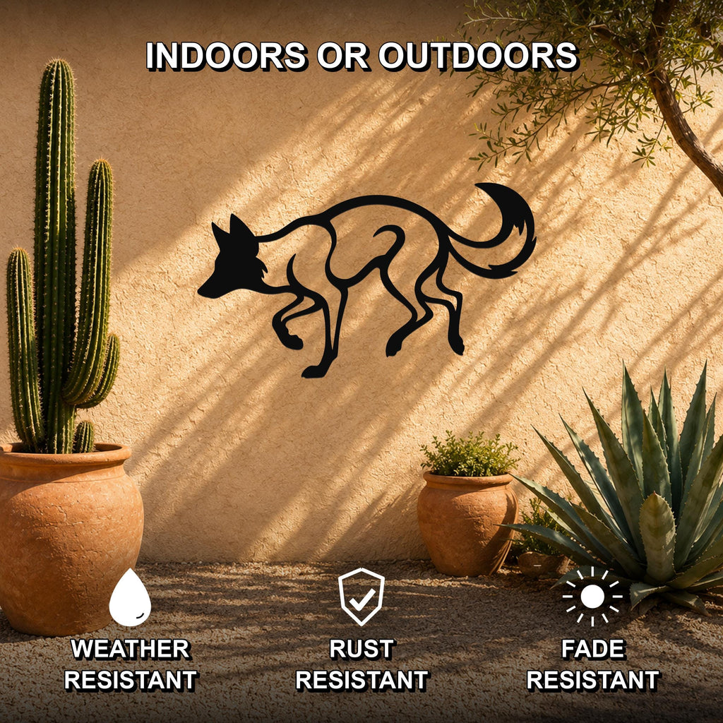 Black metal coyote wall art silhouette with cutout details, mounted on an outdoor stucco wall beside potted cacti and succulents.