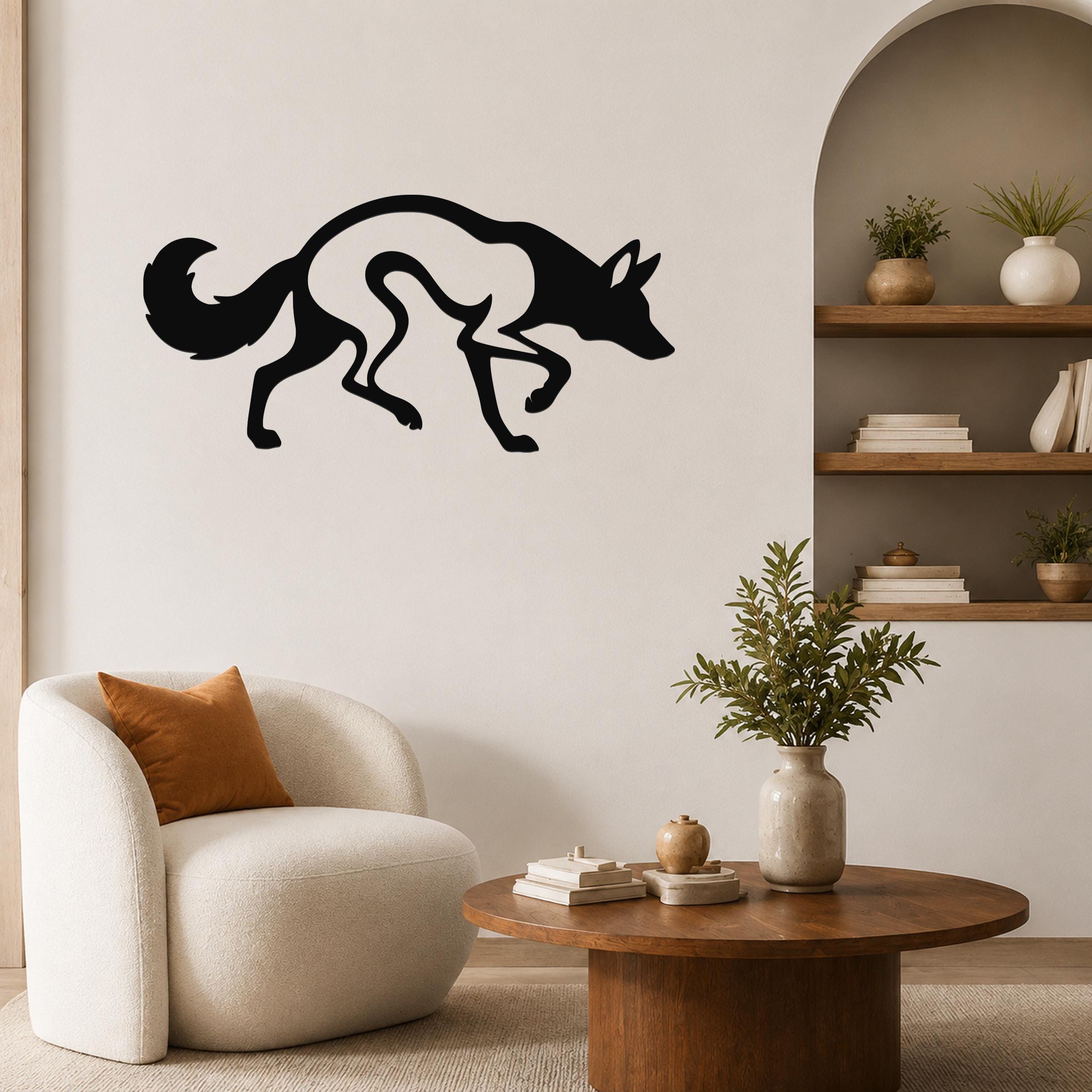 Black metal coyote wall art with a silhouette design, mounted on a living room wall above a round wooden coffee table.