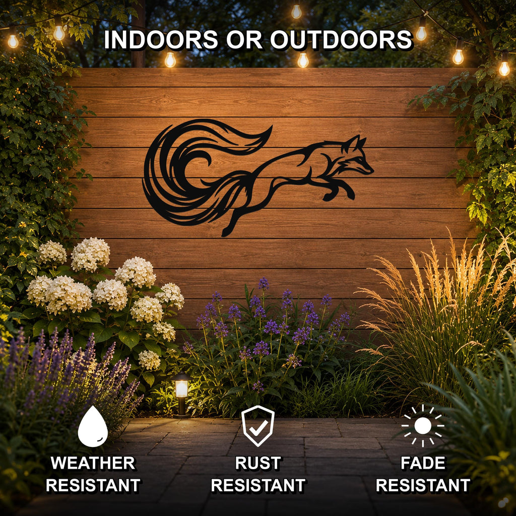 Black metal fox wall art with a flowing tail silhouette, mounted on a wooden outdoor wall surrounded by plants and string lights.