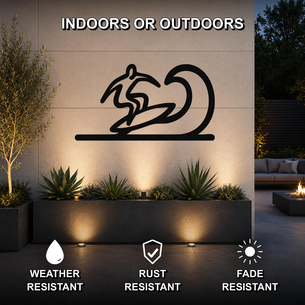 Black metal surfer wall art with wave silhouette, mounted on an outdoor wall above a planter in a modern patio setting.