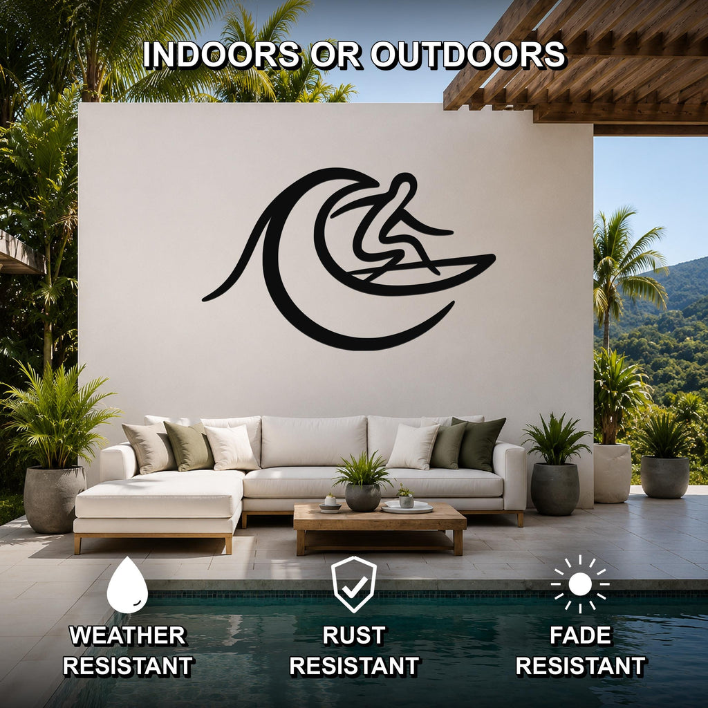 Black metal surfer wall art with wave cutout, mounted on a white outdoor wall above a sofa in a patio living area.