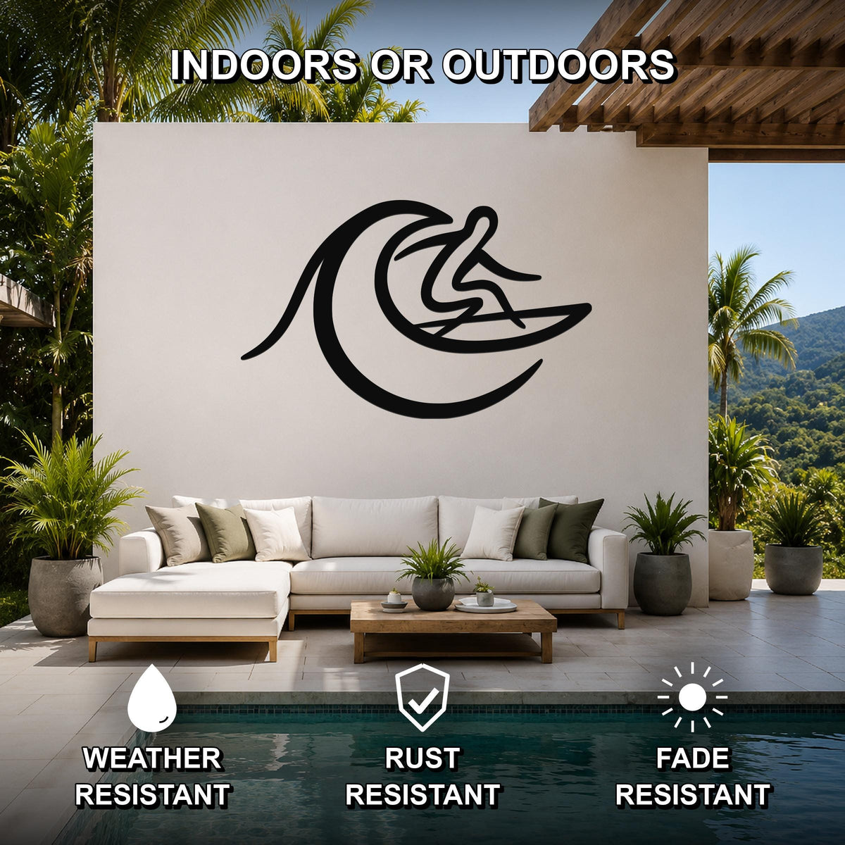 Black metal surfer wall art with wave cutout, mounted on a white outdoor wall above a sofa in a patio living area.