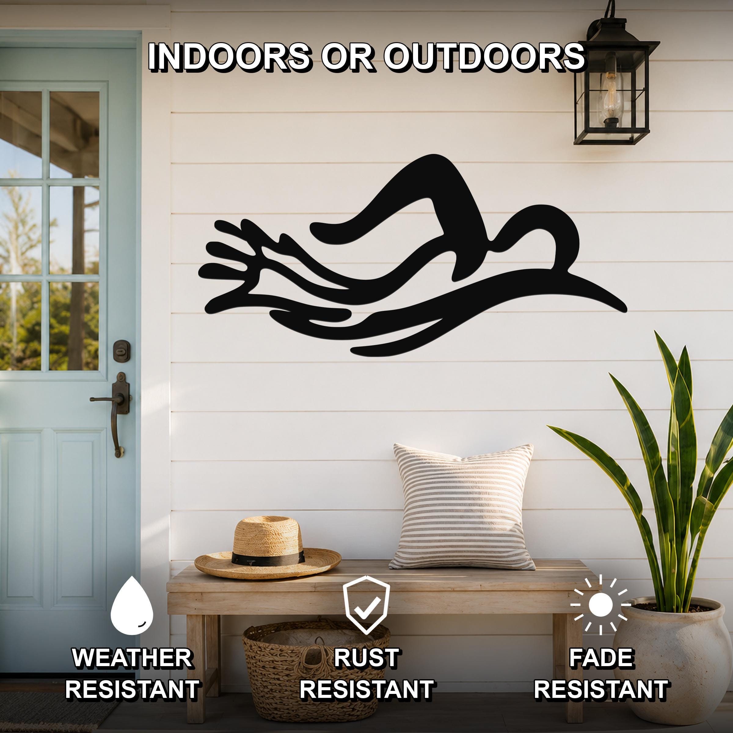 Black metal wall art in the silhouette of a swimmer in motion, mounted on a white shiplap wall above a wooden bench on a porch.
