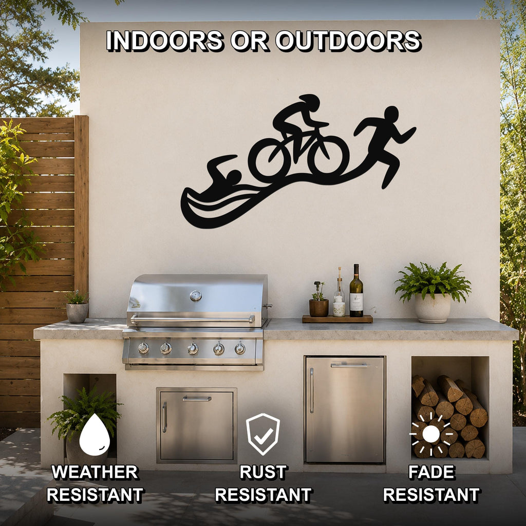 Black metal triathlon wall art with swim, bike, and run silhouettes, mounted on an outdoor patio wall above a grill and counter.