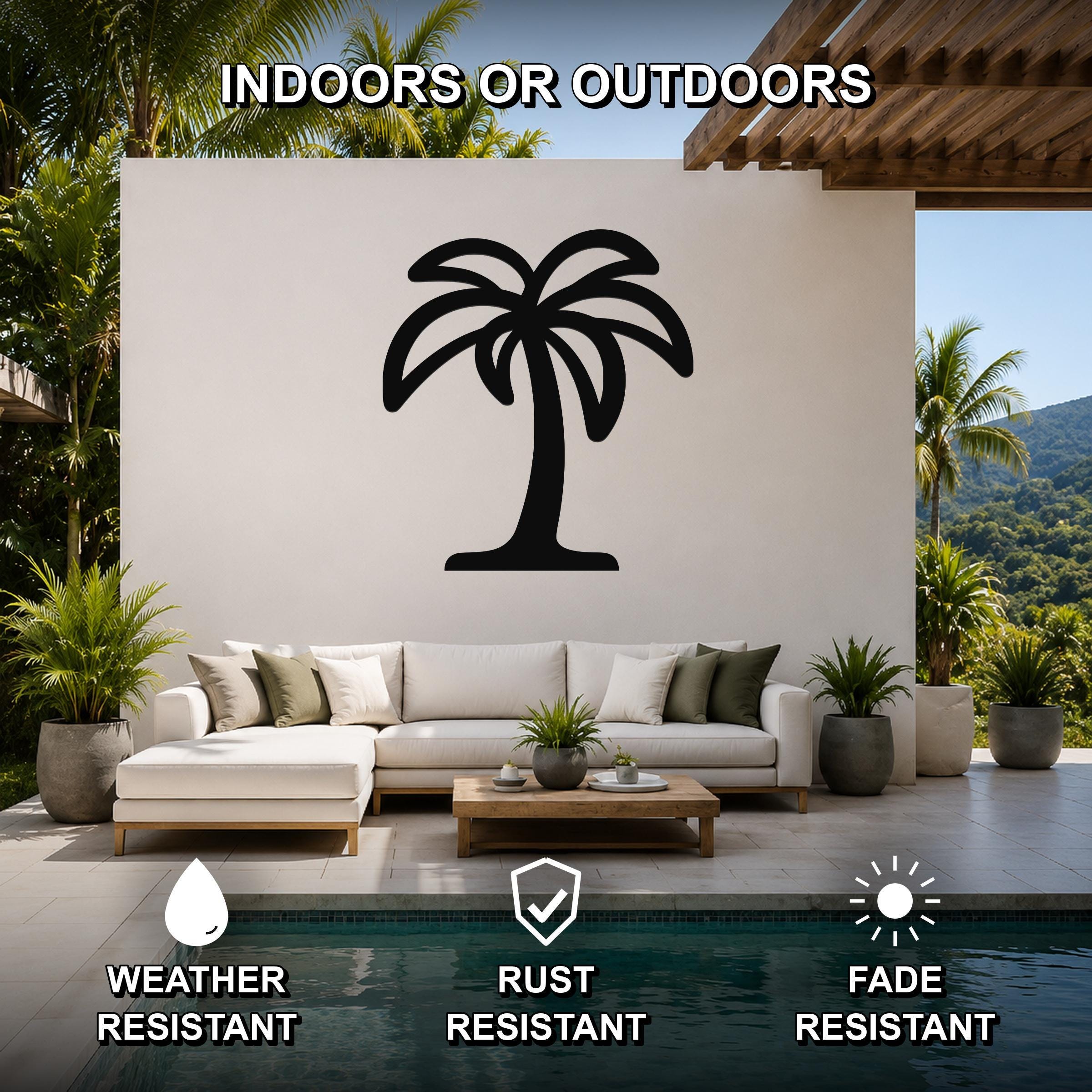 Black metal palm tree wall art with a silhouette design, mounted on a white outdoor wall above a sofa in a patio living area.