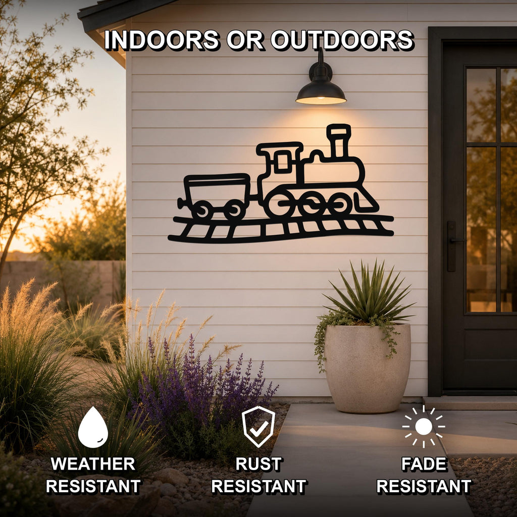 Black metal train wall art with a silhouette of a locomotive and car on tracks, mounted on a white exterior wall above a patio with plants.