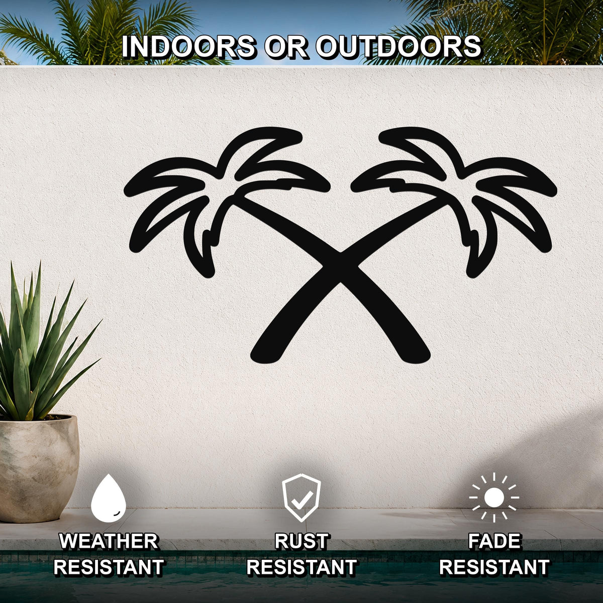 Black metal wall art featuring a silhouette of two crossed palm trees, mounted on an outdoor wall above a pool with a potted plant nearby.
