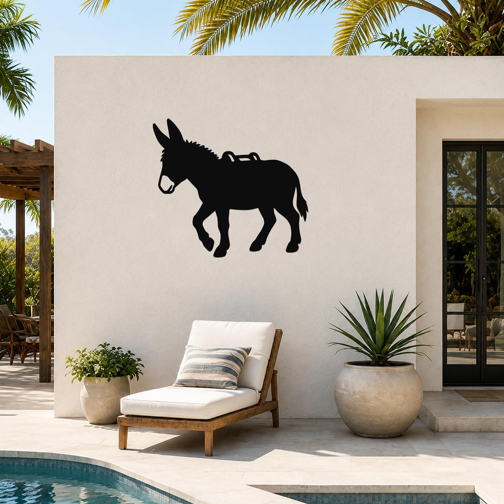 Black metal burro silhouette wall art with saddle cutout, mounted on an outdoor patio wall above a lounge chair near a pool.