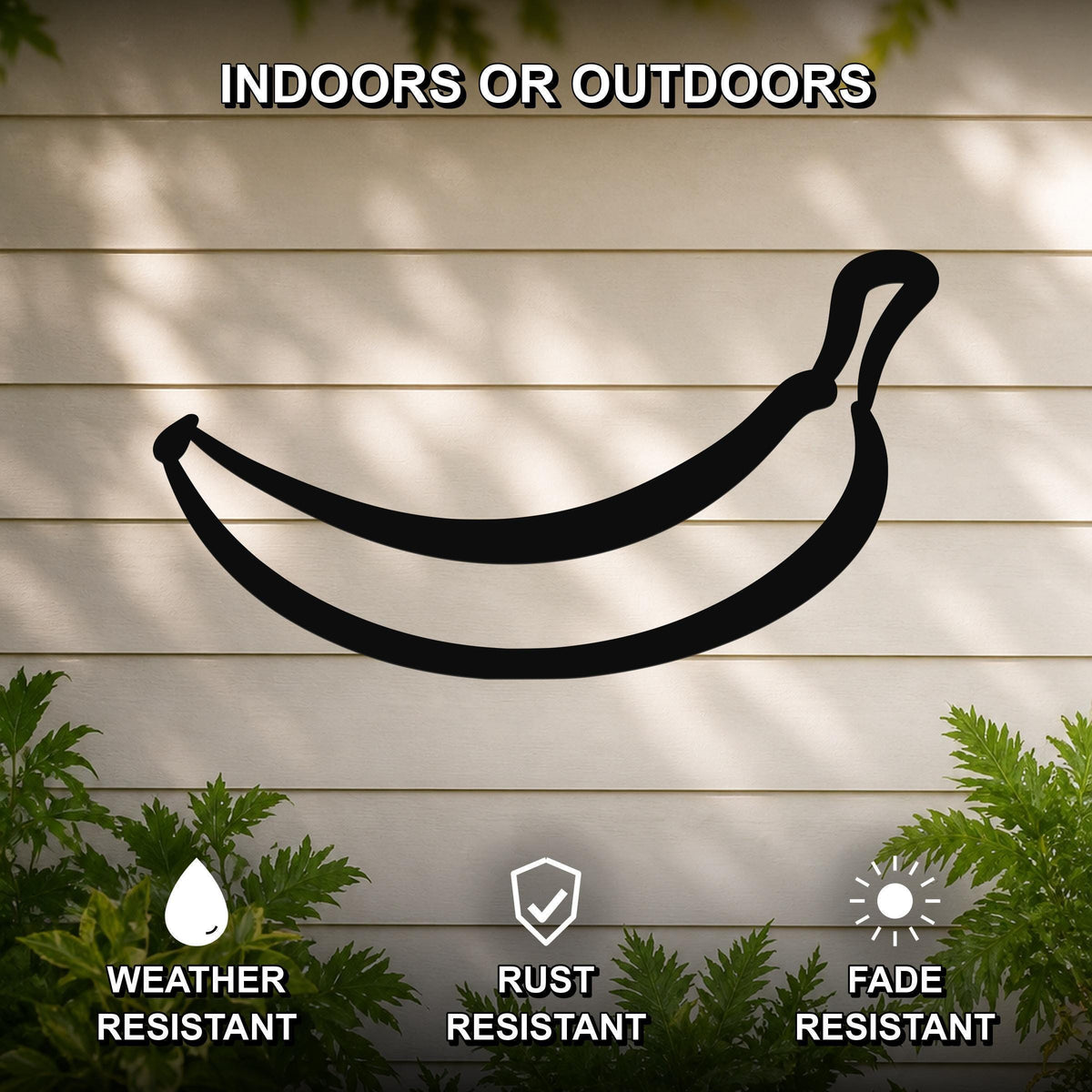 Black metal banana wall art silhouette mounted on a beige outdoor wall, with green plants at the base and text indicating it is weather, rust, and fade resistant.