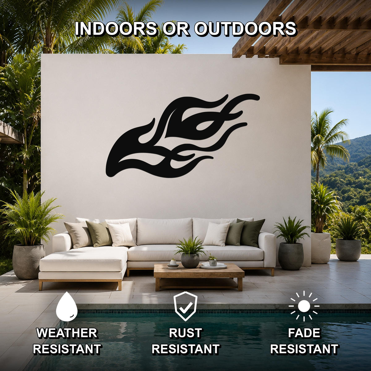 Black metal flame wall art with flowing silhouette cutouts, mounted on a white outdoor wall above a sofa in a patio living area.