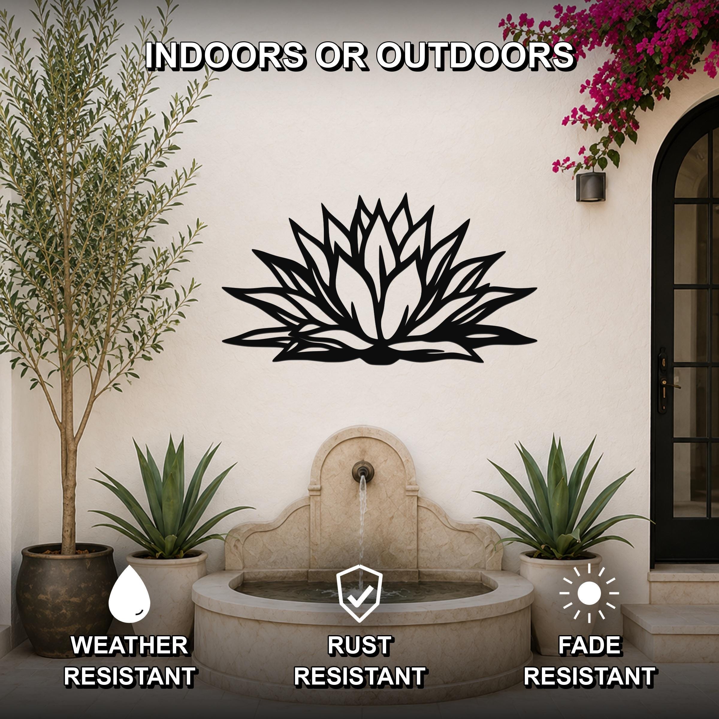 Black metal agave wall art with bold geometric cutouts, mounted on an outdoor wall above a stone fountain in a patio setting.