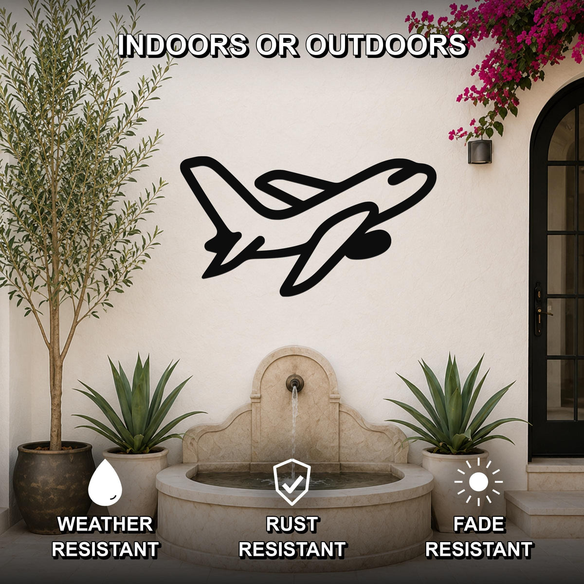 Black metal airplane wall art silhouette mounted on an outdoor patio wall above a stone fountain, flanked by potted plants and a flowering vine.