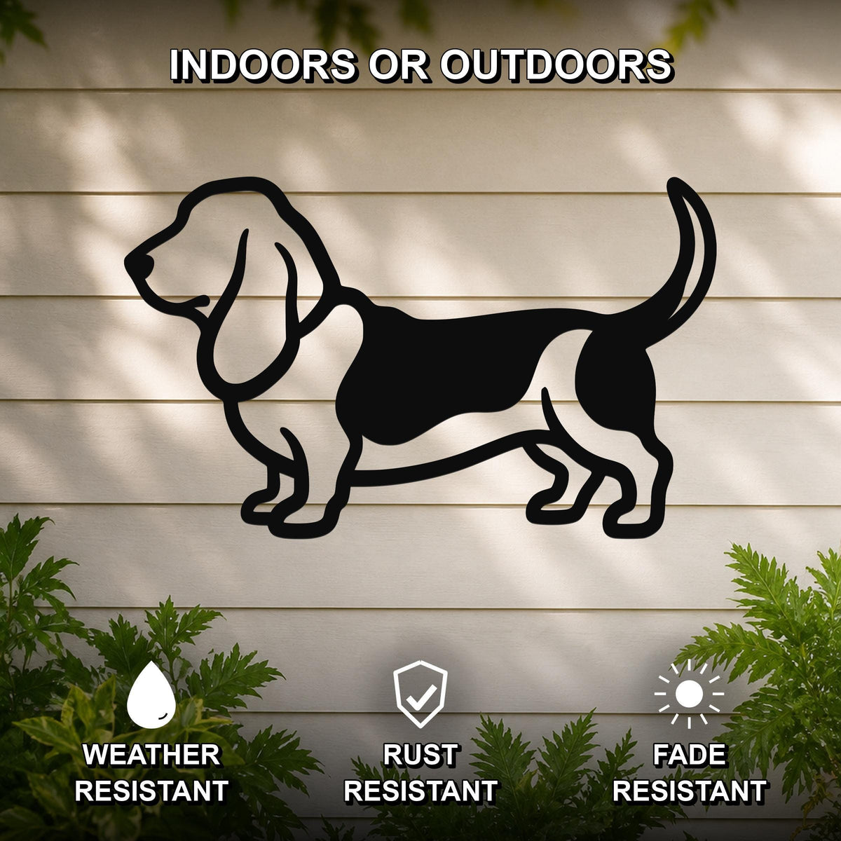 Black metal Basset Hound wall art silhouette mounted on a light-colored outdoor wall, with green plants at the base and text indicating it is weather, rust, and fade resistant.