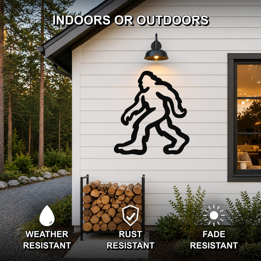 Black metal Bigfoot silhouette wall art mounted on a white siding exterior wall above a firewood rack, with text indicating it is weather, rust, and fade resistant for indoor or outdoor use.