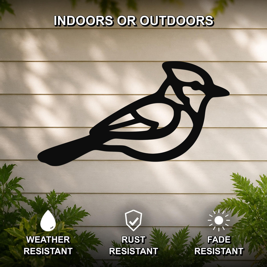 Black metal blue jay wall art with internal cutout details, mounted on a light-colored outdoor wall with greenery below.