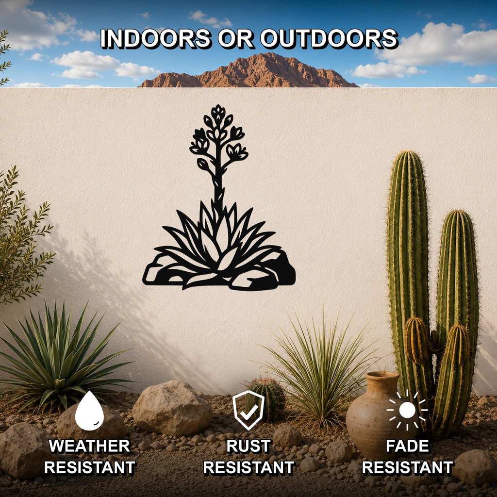 Black metal agave wall art with blooming flower cutout, mounted on a white outdoor wall in a desert garden setting.