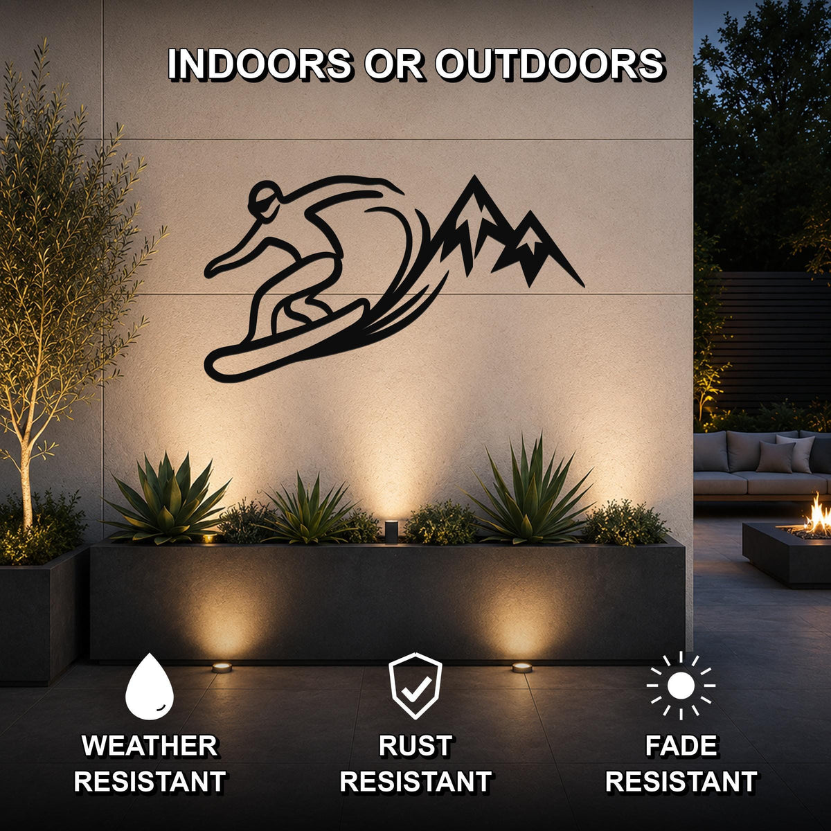 Black metal wall art silhouette of a snowboarder and mountains, mounted on an outdoor wall above a planter in a patio setting.